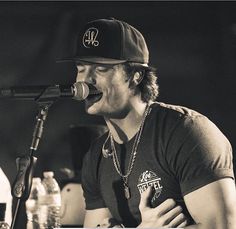 a man singing into a microphone while wearing a hat