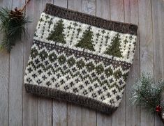 a knitted christmas stocking sitting on top of a wooden floor next to pine cones