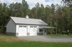 a man on a tractor in front of a garage with two doors and a roof