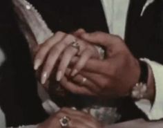 a man and woman holding each other's hands with wedding rings on their fingers