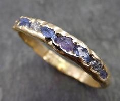 a yellow gold ring with blue sapphires and diamonds on the inside, sitting on a gray surface