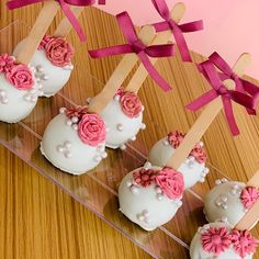 four cake pops decorated with pink flowers and wooden skewers