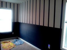 an empty room with black and white stripes painted on the wall next to a window