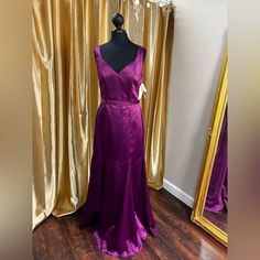 a mannequin dressed in a purple dress next to a gold curtain and mirror