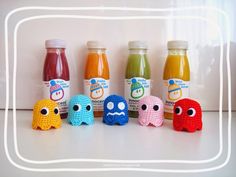 six crocheted toys are lined up next to each other with juice in the background