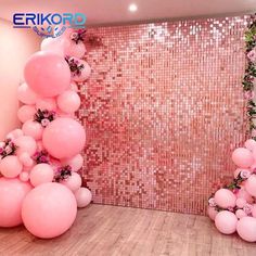 pink balloons and greenery are arranged in the corner of a room that is decorated with sequins