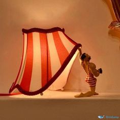 a lamp that is sitting on top of a table next to a stuffed animal with a red and white striped umbrella