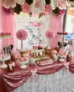 a baby shower party with pink and gold decorations, elephant cake toppers, cupcakes, and paper flowers