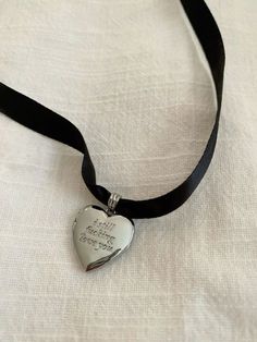 a silver heart shaped pendant on a black ribbon