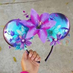 a hand holding a purple and blue mask with flowers on it