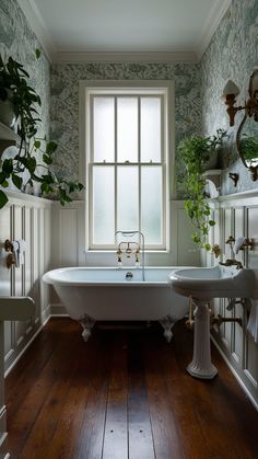 an old fashioned bathtub and pedestal sink in a bathroom with wood floors, wallpapered walls and windows