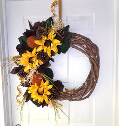 a wreath with sunflowers and pine cones hangs on the front door