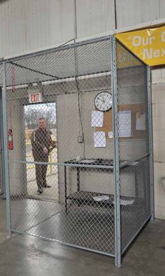 a man standing in an enclosed area next to a clock