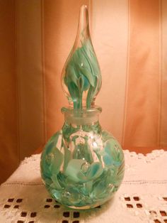 a green glass vase sitting on top of a white doily next to a wall