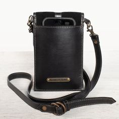 Inspired by the timeless charm of countryside equestrian life, the Devon Phone Tote in Italian leather and black suede brings both elegance and functionality. Highlighted by a custom horse stirrup design, this tote features a magnetic flap concealing credit card slots, while the interior holds any smartphone and essentials. The back sleeve offers quick access for those on the go. Perfect for stable outings or city evenings, this leather crossbody bag merges classic equestrian style with modern p Leather Phone Bag, Accesories Jewelry, Custom Horse, Vanity Bag, Lucky Horseshoe, Equestrian Life, Black On Black, Stirrups, Equestrian Style