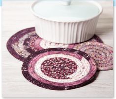 three coasters with designs on them sitting next to a white bowl and saucer