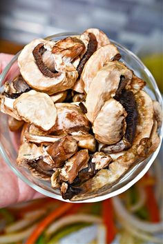 a person holding a glass bowl filled with mushrooms