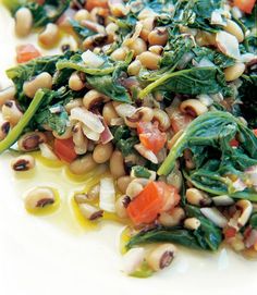 a white plate topped with spinach, carrots and other food items on top of it