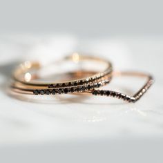 two thin gold rings with black diamonds on them sitting on a white tablecloth in front of the camera