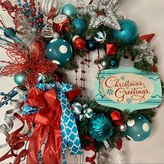 a christmas wreath hanging on the side of a wall with ornaments around it and an ornament that reads, christmas greetings