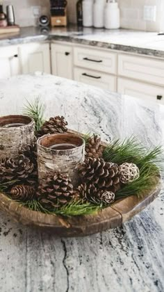 some pine cones are sitting on a wooden tray in the middle of a kitchen counter