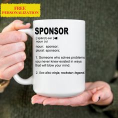 a person holding a white coffee mug with the words sponsor printed on it in black