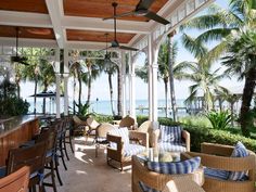 an outdoor bar with wicker chairs and palm trees on the beach in front of it