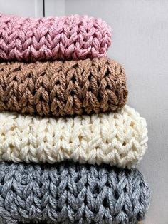 four crocheted blankets stacked on top of each other in different colors and sizes