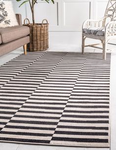 a black and white area rug in a living room with two wicker chairs next to it