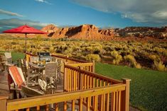 a deck with chairs and an umbrella in the middle of a desert area near mountains