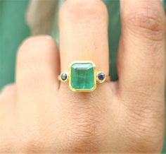 a woman's hand with a ring on it and an emerald stone in the middle