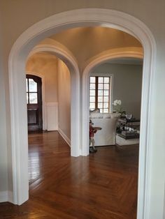 an archway leading into a living room with hard wood flooring and white trim on the walls