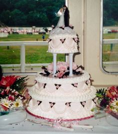 a three tiered wedding cake sitting on top of a table next to some flowers