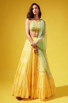 Yellow georgette tiered lehenga with all-over embroidered motifs and gathered detailing. Paired with halter neck silk embroidered blouse and tulle dupatta with bead tassel detailing at hem.
Component: 3
Pattern: Embroidered
Neckline: Halter neck
Sleeve Type: Sleeveless
Fabric: Lehenga: Georgette, Blouse: Silk, Dupatta: Tulle
Color: Yellow
Other Details: 
Open back blouse
Criss-cross tie-up at back
Tasseled hem dupatta
Occasion: Mehendi and Haldi - Aza Fashions Yellow Skirt Outfit Indian, Haldi Outfits For Bridesmaid, Halter Neck Blouses, Haldi Outfit, Yellow Lehenga, Indian Outfits Lehenga, Green Tulle, Fabric Skirt, Blouse Silk