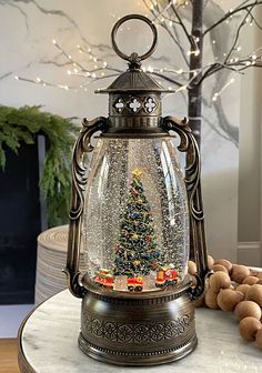 a snow globe with a christmas tree in it on a table next to some nuts