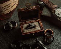 an old wooden box with two wedding rings in it and other accessories around it on a table