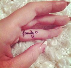 a person's hand with a small tattoo on it that says, family in the middle