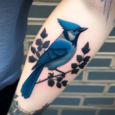 a blue bird sitting on top of a tree branch with leaves and berries around it