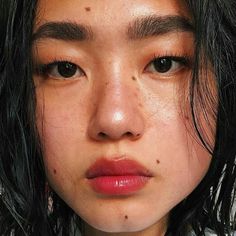 a close up of a person with freckles on her face and black hair