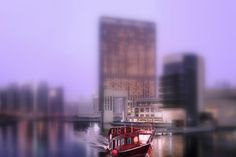 a red boat floating on top of a river next to tall buildings in the background