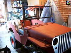 an old jeep is being worked on in a garage