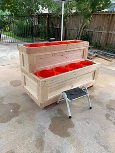 a wooden bench with red buckets on it and an umbrella in the back ground