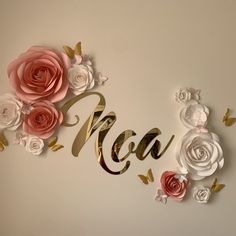 a wall with paper flowers and the word mom spelled out in gold lettering on it