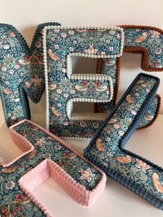 several pieces of blue and pink fabric are arranged in the shape of letter e, with flowers on them