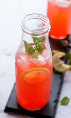 two mason jars filled with lemonade and mint garnish on a black tray