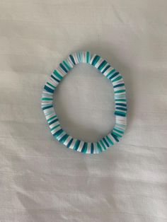 a blue and white bracelet sitting on top of a bed next to a pillow cover