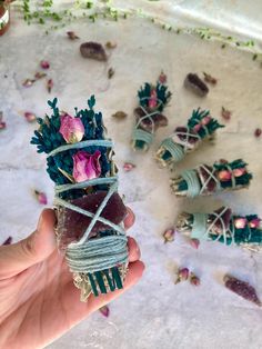 a person holding up some kind of plant with flowers on it's stems and wrapped in twine