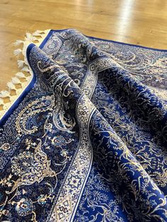 a blue and white rug on the floor with an intricate design in gold trimmings