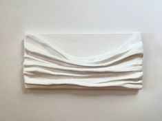 a folded piece of cloth sitting on top of a white table next to a wall