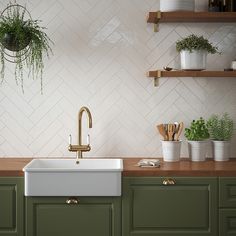 a kitchen with green cabinets and white tiled backsplash, brass faucet